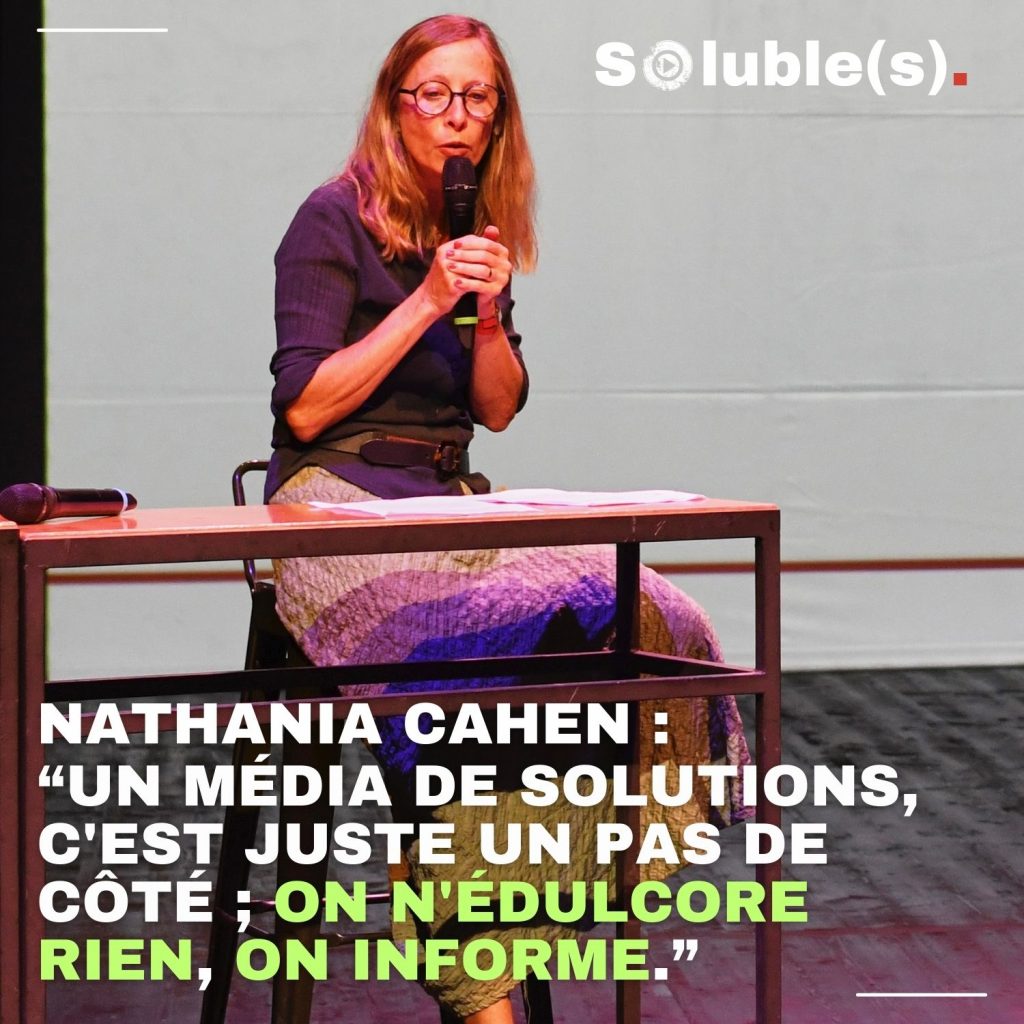 Pooto de Nathania Cahen, sur scène lors d'une présentation de Marcelle. Citation écrite dans l'image : “UN MÉDIA DE SOLUTIONS, C'EST JUSTE UN PAS DE CÔTÉ ; ON N'ÉDULCORE RIEN, ON INFORME.” NATHANIA CAHEN :