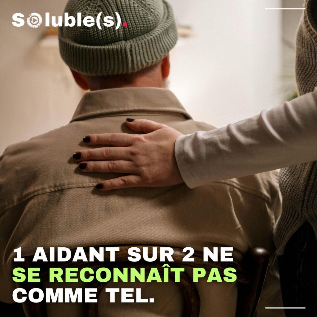 La main "jeune" d'une femme sur le dos d'un homme assis de dos qui porte une veste et un bonnet kaki. Texte : 1 AIDANT SUR 2 NE SE RECONNAÎT PAS COMME TEL.