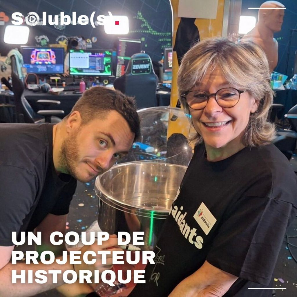 Photo de Zeraptor, l'organisateur du ZEVENT avec une personne de l'association françaises des aidants. Elle porte un T-shirt noir ciglé : "Les Zaidants" (jeu de mots)Texte sur la photo : UN COUP DE PROJECTEUR HISTORIQUE