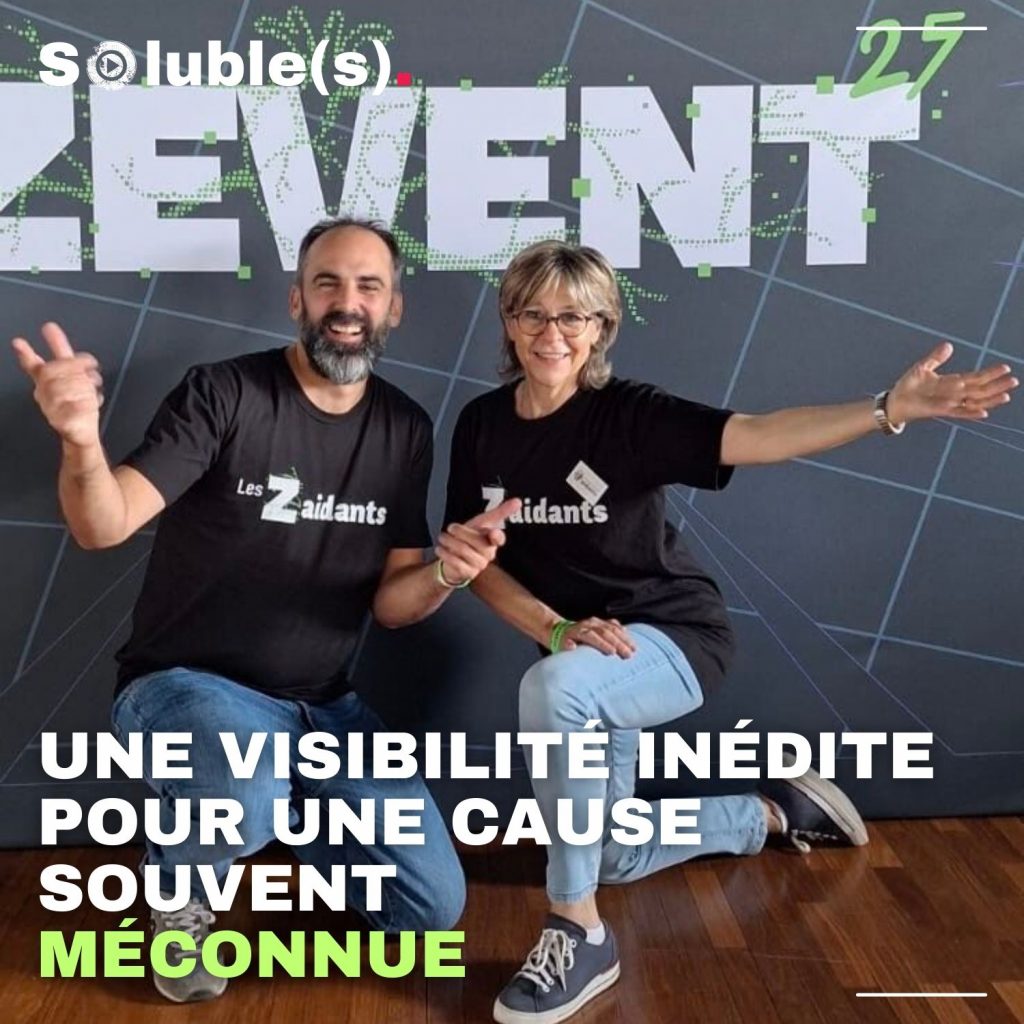 Photo de Simon de Grenelle et d'une autre personne de l'association française des aidants. Les deux posent joyeusement devant un panneau / mur ciglé du logo ZEVENT 25 Texte sur l'image : UNE VISIBILITÉ INÉDITE POUR UNE CAUSE SOUVENT MÉCONNUE