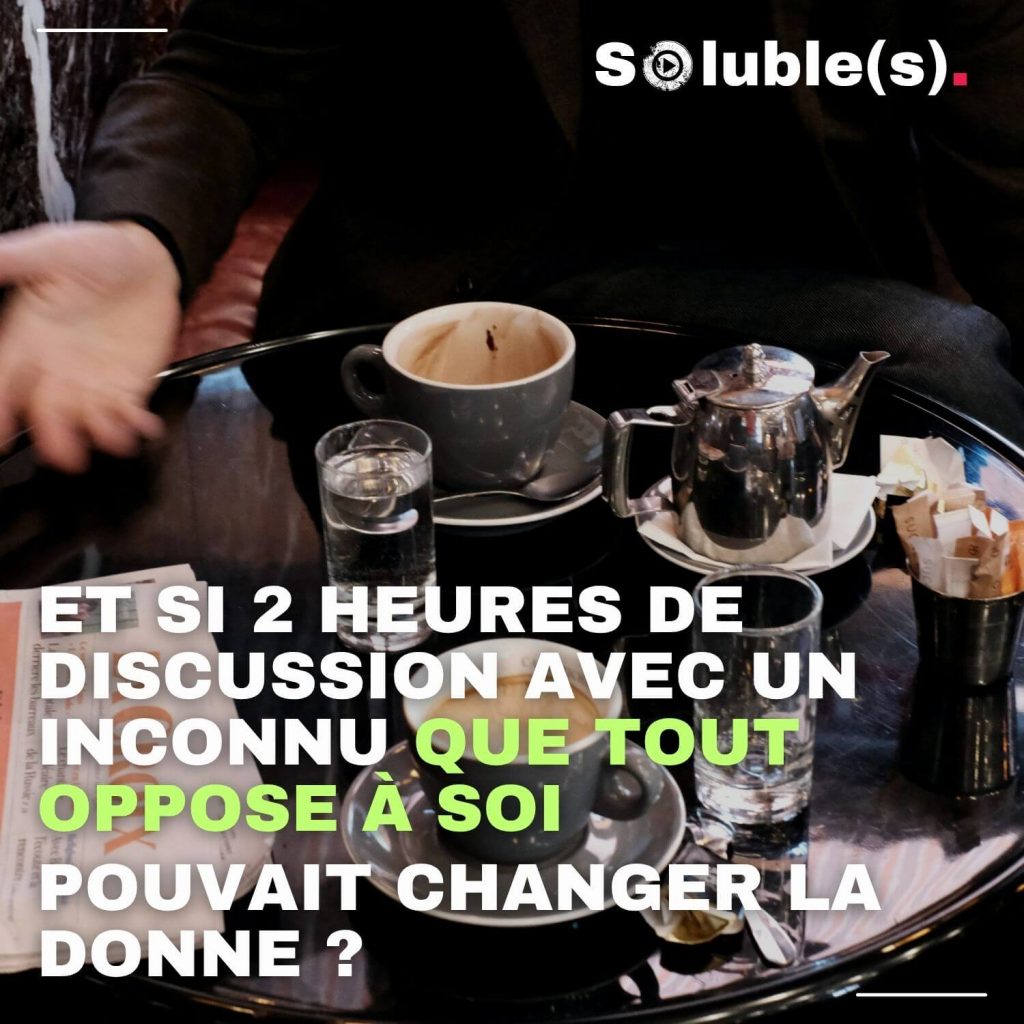 Table de café vue rapprochée avec deux tasses à moitié vides, verres et théière en métal, ponctuée de mains gesticulant en pleine discussion. Texte surimprimé : “Et si 2 heures de discussion avec un inconnu que tout oppose à soi pouvait changer la donne ?”. L’image illustre le défi et l’espoir d’un vrai dialogue entre personnes opposées, thème central de l’épisode “Faut qu’on parle” du podcast Soluble(s) avec Béatrice Bouniol.