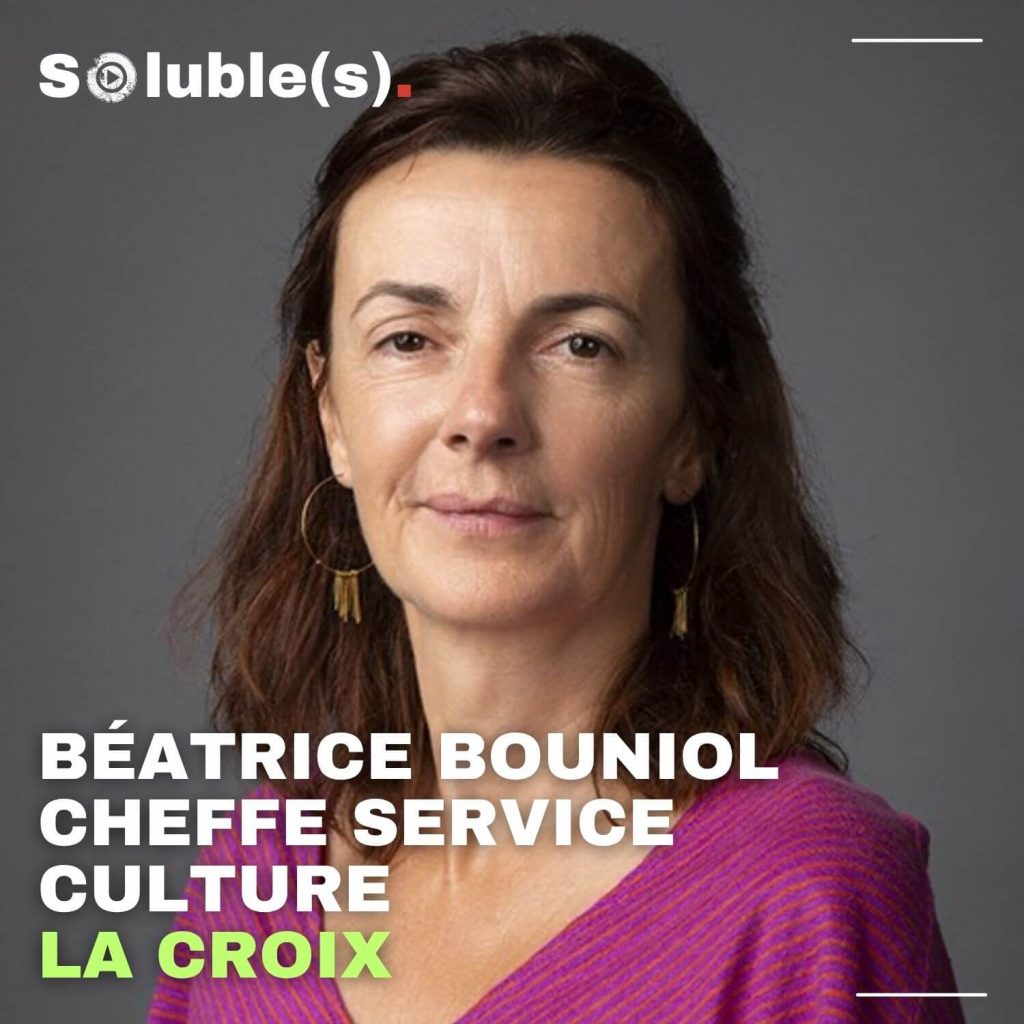 Portrait professionnel de Béatrice Bouniol, cheffe du service culture à La Croix, portant un haut violet et affichant un sourire discret, sur fond neutre gris. Son nom et sa fonction sont indiqués en bas de l’image. Ce visuel incarne la voix experte et le point de vue journalistique de l’épisode “Faut qu’on parle” dans le podcast Soluble(s).