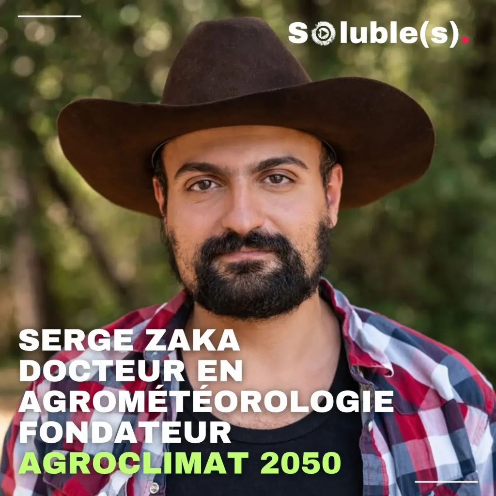 Portrait en plan rapproché de Serge Zaka, un homme à la barbe brune portant un chapeau marron et une chemise à carreaux rouge et bleue sur un t-shirt noir. Le fond est composé d'arbres flous. En bas à gauche, le texte indique en lettres capitales blanches et vertes : "Serge Zaka, Docteur en agrométéorologie, Fondateur Agroclimat 2050". Le logo Soluble(s) apparaît en haut à droite.